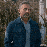 a man with a beard wearing a blue jacket and a grey sweater with netflix written on the bottom