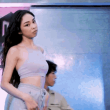 a woman in a crop top is standing in front of a man