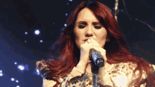 a woman with red hair is singing into a microphone on stage