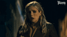 a woman in a dark room with the boys written on the bottom right