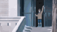 a boy in a brown jacket and red hat is standing in front of a door waving