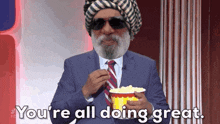 a man in a suit and tie eating popcorn with the words you 're all doing great