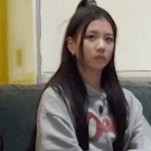 a girl with long hair is sitting on a couch and looking at the camera .