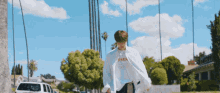 a man wearing a white shirt that says reer walking down a street