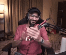 a man wearing headphones is sitting in front of a microphone and clapping .