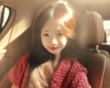 a woman in a red plaid shirt sits in a car seat