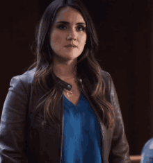 a woman wearing a blue shirt and a leather jacket