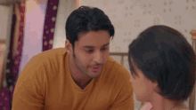 a man in a yellow shirt is looking at a woman