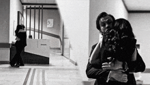 a black and white photo of a man and woman hugging in front of a desk that says damla on it