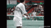 a tennis player holds a tennis racquet in front of a sign that says ' cc '
