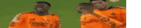 a group of soccer players wearing orange jerseys are standing next to each other on a field .