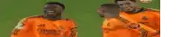a group of soccer players wearing orange jerseys are standing next to each other on a field .