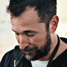 a man with a beard is wearing a lanyard around his neck with the letter j on it