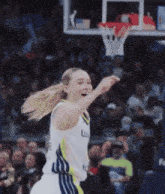 a female basketball player wearing a white and blue uniform with the letter l on the front