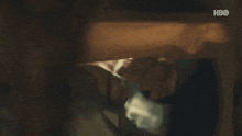 a person is laying under a bed with a hbo logo on the bottom right corner .