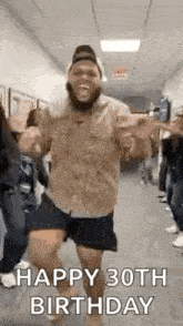 a man with a beard is dancing in a hallway while a group of people celebrate his 30th birthday .