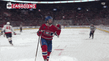 a hockey player in a red white and blue uniform celebrates his goal