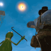 kermit the frog is holding a cane in front of a cowboy