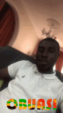 a man sitting on a couch with the word obusi written on his chest