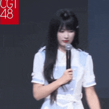 a girl is holding a microphone in front of a sign that says cgi48