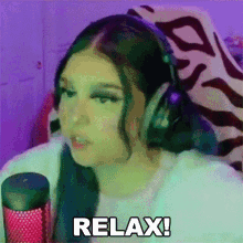 a girl wearing headphones is sitting in front of a microphone and saying `` relax '' .
