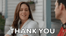a woman is smiling and saying thank you while looking at a man on a porch .