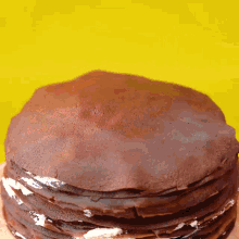 a close up of a stack of chocolate pancakes on a yellow background