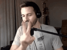 a man wearing headphones is talking into a microphone while holding a cell phone .