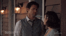 a man and woman are standing next to each other in front of a sign that says hallmark on it