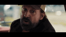 a man with long hair and a beard wearing a baseball cap