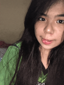 a girl wearing a green shirt that says ucsd sticks her tongue out