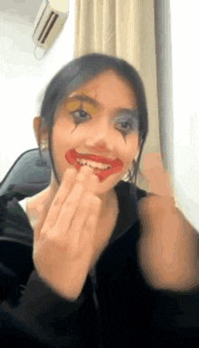 a woman with clown makeup on her face is smiling and making a face .