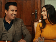 a man and woman are sitting at a table and smiling
