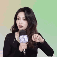 a woman in a black dress is holding a microphone .