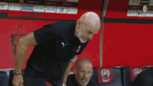 a bald man with a beard wearing a puma shirt