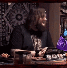 a man with a beard is sitting at a table with a tablet