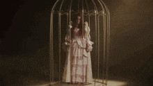 a woman in a pink dress is sitting in a cage