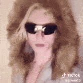 a woman wearing sunglasses and a suit is a tik tok video .