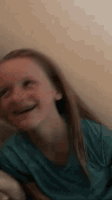 a young girl in a blue shirt is smiling and making a face .