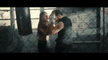 a man and woman boxing in front of a punching bag that says " the unbeatable "