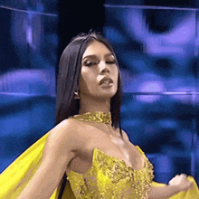 a woman is wearing a yellow dress and a gold necklace .