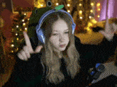 a girl wearing headphones and a frog hat is pointing up