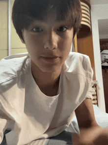 a young man in a white t-shirt looks at the camera