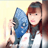 a woman wearing headphones holds a blue fan in front of a screen that says ii