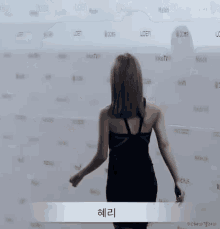 a woman in a black dress is dancing in front of a wall that says melon