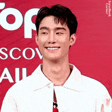 a young man is smiling in front of a sign that says scov all