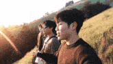 a group of young men are standing on top of a grass covered hill