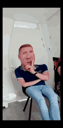 a man is sitting in a chair with his hand on his chin and a fake face on his face