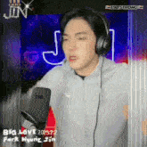 a man wearing headphones stands in front of a microphone that says t98 strong on it