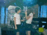 two girls are standing next to each other and one is singing into a microphone while the other looks on ..